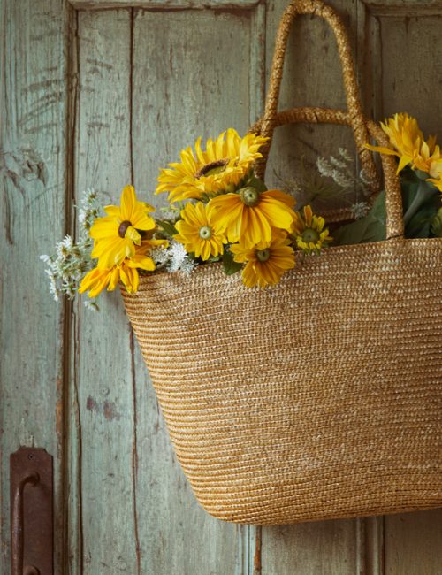 Straw purse with sunflowers on old door