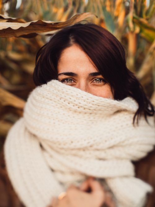 Young woman with her face covered in a cozy warm scarf.